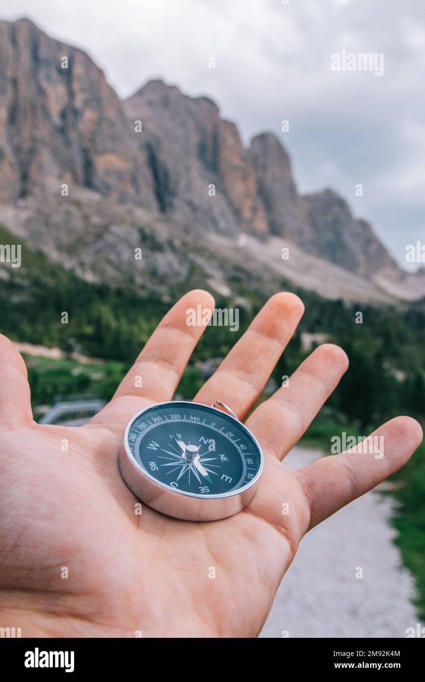 Hand mit Kompass in der Berglandschaft der Dolomiten. Junger Entdecker, der den Kompass in der Hand hält. Konzept von Reisen, Freiheit, Lebensstil, Versuch Stockfoto