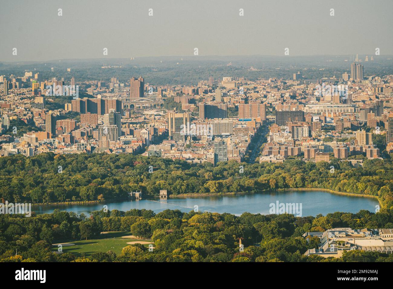 Blick auf den Central Park mit Fluss und üppigen Bäumen im Zentrum von New York in der Nähe von Wohngebäuden Stockfoto