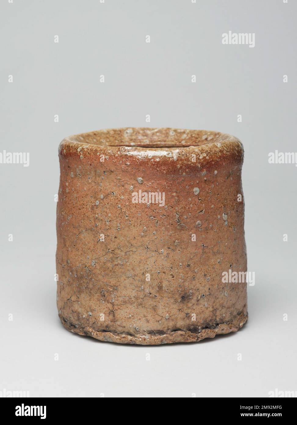 Shigaraki Ware Mizusashi (Teezeremonie Süßwasserdose) Shigaraki Ware Mizusashi (Teezeremonie Süßwasserdose), ca. 1620" Steingut mit Ascheglasur, Lackdeckel; Shigaraki-Geschirr, 6 x 6 1/2" (15,2 x 16,5 cm). Während die meisten Töpfer darauf achten, Steine aus ihrem Lehm zu filtern, verstehen die Töpfer aus der Region Shigaraki, dass die durch steinige Quarzstücke und Feldspat erzeugte Textur ihre Waren taktil und visuell interessant macht. Die Handwerker fügen nur minimale Glasur hinzu, sodass die Oberfläche ihre Körnung behält. Shigaraki, östlich von Kyōto, ist seit Jahrhunderten eine Ofenanlage, die ursprünglich hergestellt wurde Stockfoto
