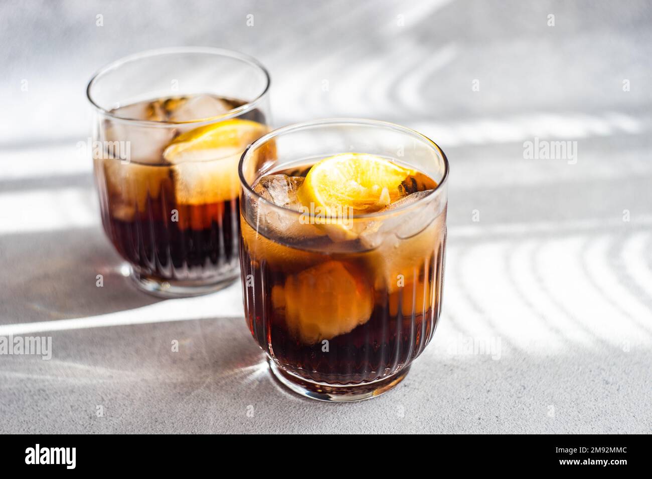 Alkohol-Cocktail Cuba Libre mit Orangenscheibe und Eis im Glas Stockfoto