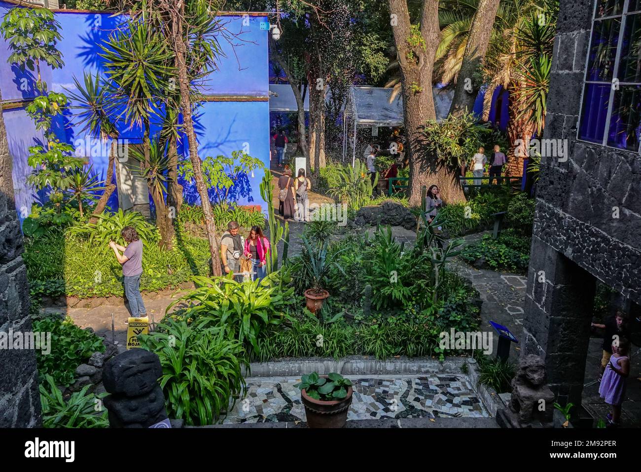 Touristen schlendern durch den Garten im Frida Kahlo Museum, auch bekannt als Blaues Haus, das dem Leben und Werk des mexikanischen Künstlers Frida Kahlo gewidmet ist, im Viertel Colonia del Carmen in Coyoacan, Mexiko-Stadt, Mexiko. Stockfoto