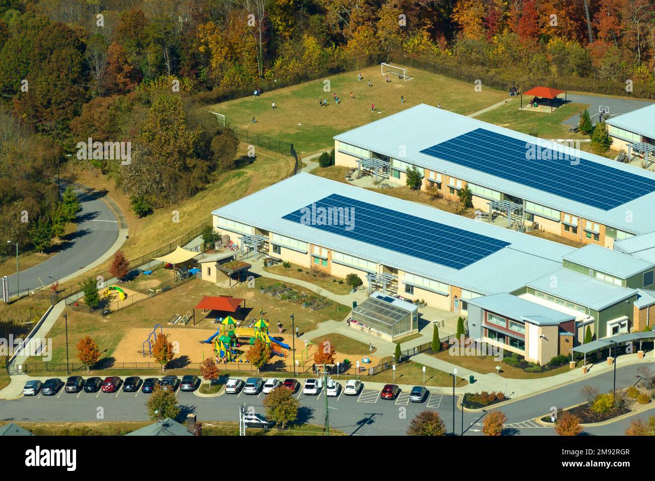 Dach des amerikanischen Schulgebäudes mit Photovoltaik-Solarpaneelen für die Stromerzeugung. Konzept für erneuerbare Energien Stockfoto
