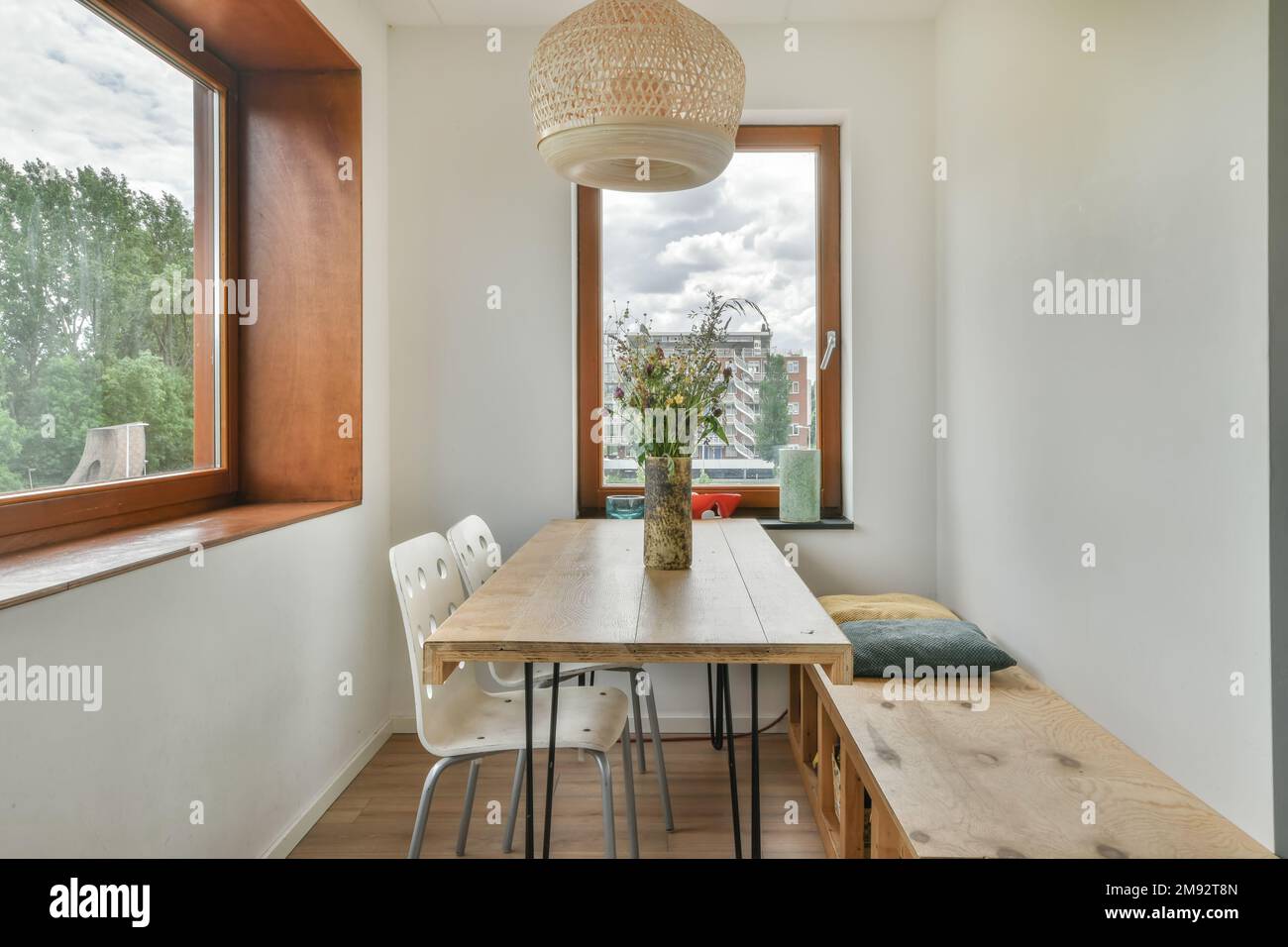Holztisch mit Vase mit Blumen im Apartment mit großem Fenster Stockfoto