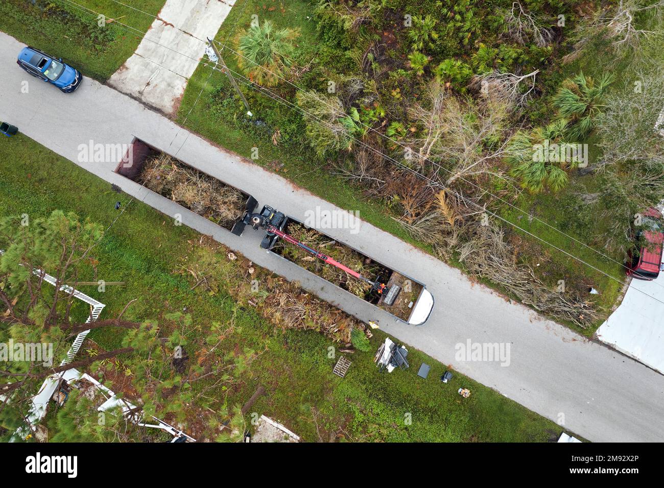 Draufsicht auf den besonderen Nachwirkungen des Unwehen-Rückgewinnungs-Muldenkipper des Unwrts, der Baumzweige aus ländlichen Straßen Floridas aufsammelt. Umgang mit Konsequenzen Stockfoto