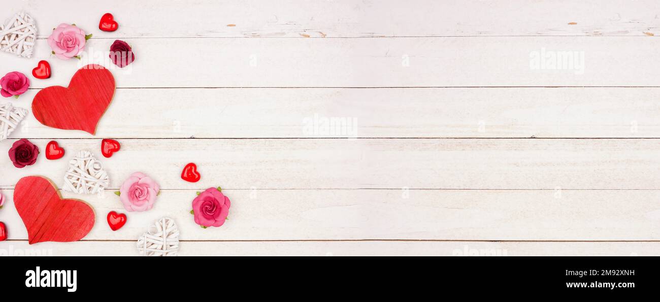 Valentinstag-Banner mit Herzensrand, Blumen und Dekor vor rustikalem weißen Holzhintergrund. Speicherplatz kopieren. Stockfoto