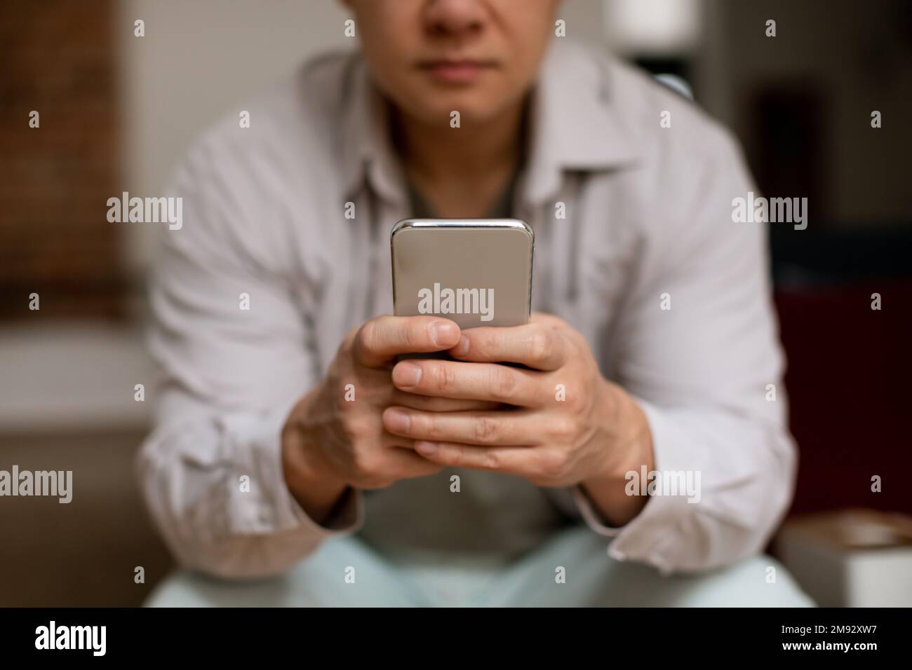 Reifer asiatischer Mann, der ein Smartphone benutzt, im Internet surft oder sich im Internet chattet, selektiver Fokus auf Handys mit dem Handy Stockfoto