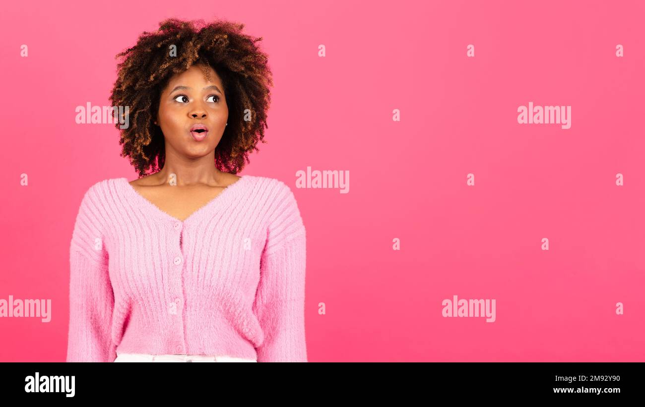 Eine überraschte junge afroamerikanische, lockige Dame mit offenem Mund, die sich einen Kopierraum ansieht Stockfoto