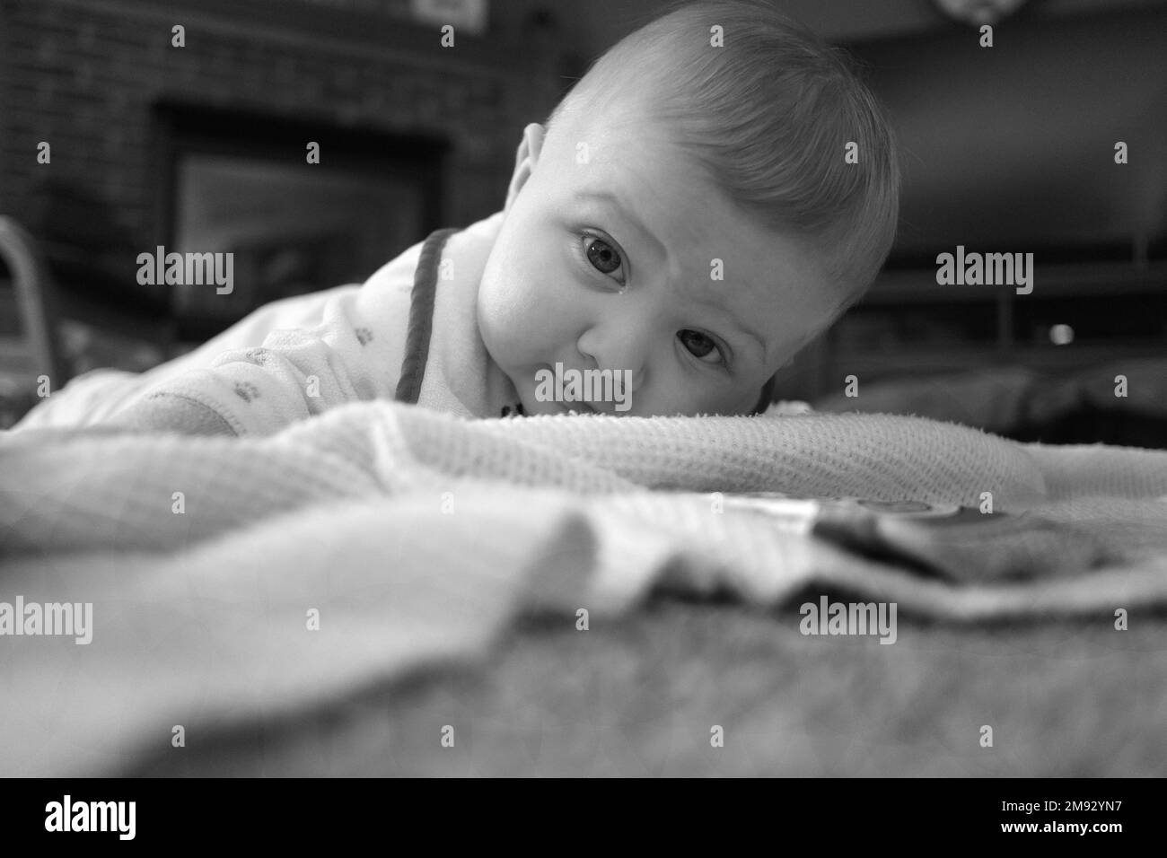 Ein fünf Monate alter Junge, der lernt, auf einer Decke zu krabbeln. Stockfoto