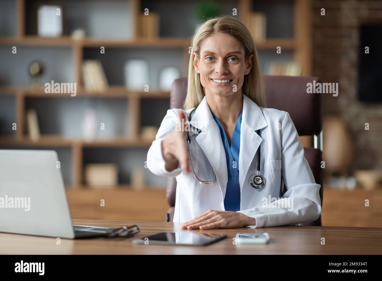 Medizinische Unterstützung. Lächelnde Ärztin, Die Hand Für Handschlag Vor Der Kamera Streckt Stockfoto