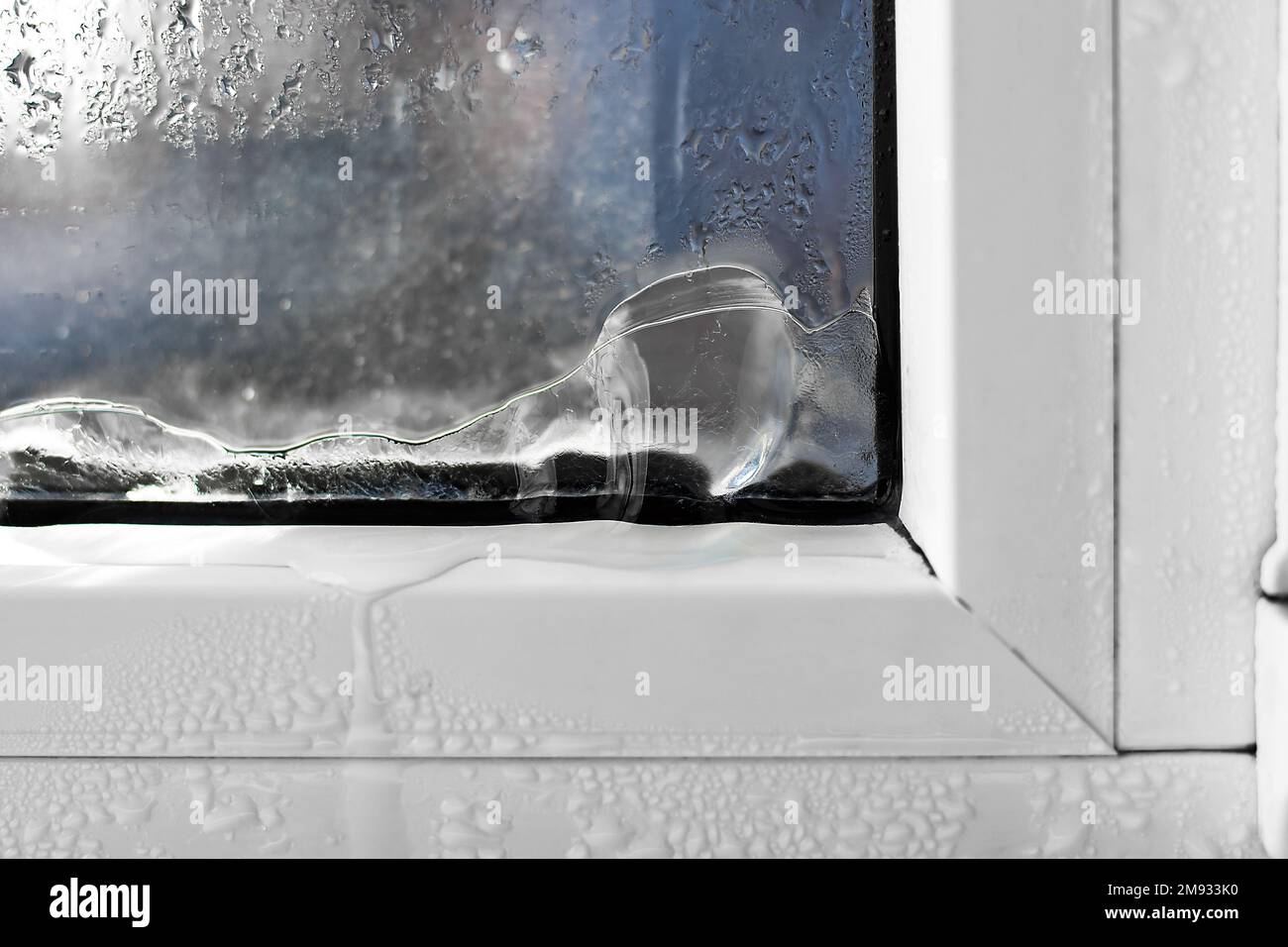 Eis bildet sich auf der Innenseite eines Fensters. Falsche Fenstermontage, Fenstereinstellung, Heizungsprobleme. Stockfoto