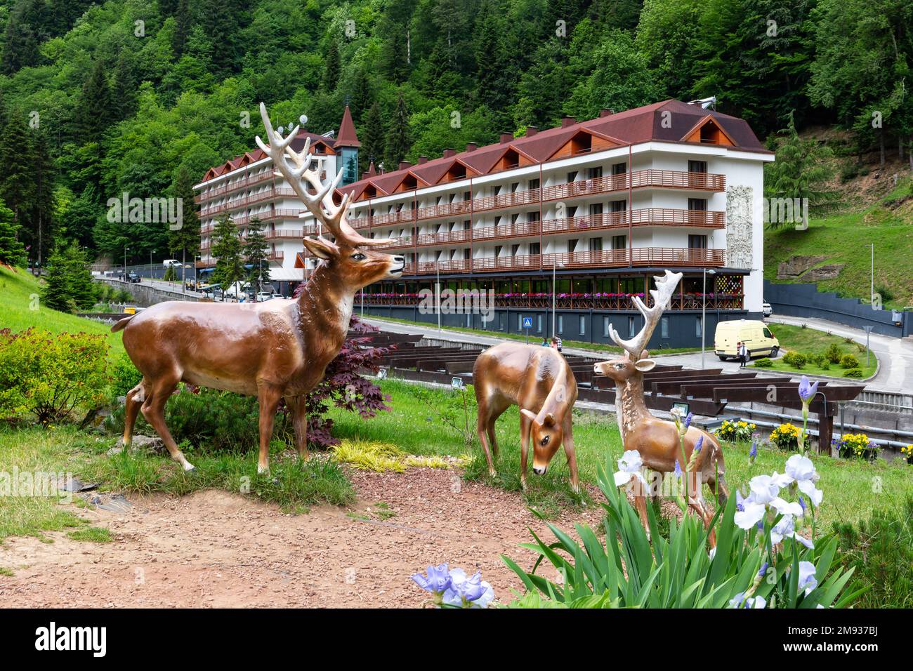 Sairme, Georgia, 06.06.21. Statuen künstlicher Hirsche, Dekoration im Kurort Sairme in den Bergen des Kleinkaukasus mit dem Sairme Hotelgebäude. Stockfoto