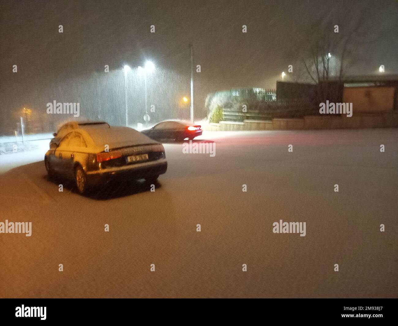 Bantry, West Cork, Irland, Montag, 16. Januar 2023; leichter Schnee fiel heute Abend in Bantry. Er klemmt am Boden, wodurch die Fahrbedingungen gefährlich werden. Die Menschen wurden daran erinnert, das Abblendlicht zu verwenden und einen zusätzlichen Abstand zum vorausfahrenden Fahrzeug zu halten. Schnee auf dem Boden des Parkplatzes des Bantry General Hospital. Kredit; ED/Alamy Live News Stockfoto