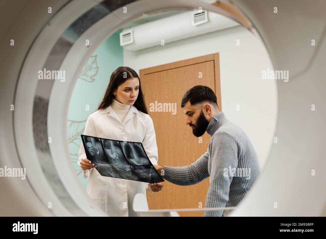 CT-Scan-Radiologe zeigt dem Patienten im Computerscanraum eine Röntgenaufnahme des Abdomens. CT-Arzt konsultiert den Patienten und zeigt dem Patienten die Thoraxröntgenaufnahme Stockfoto