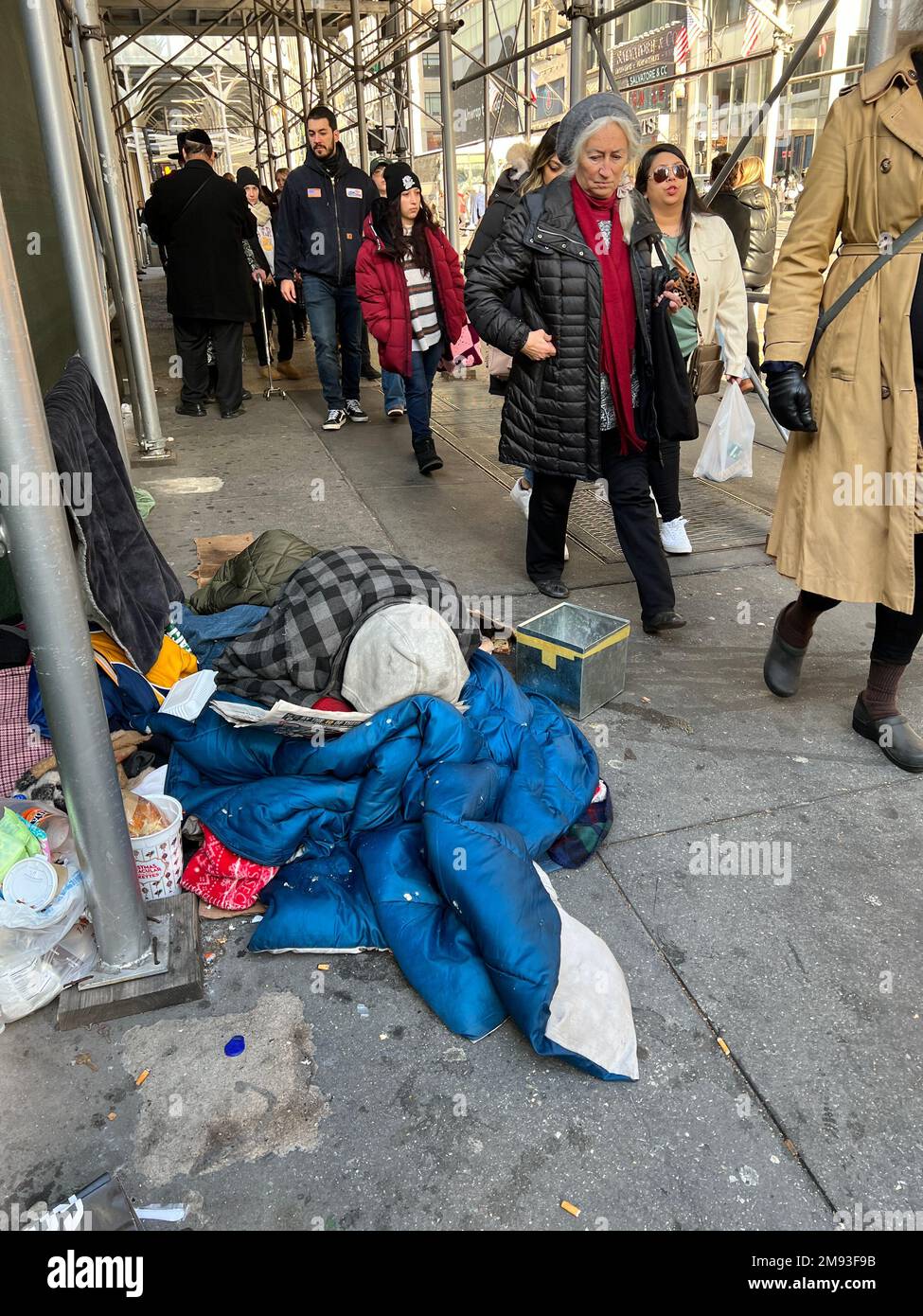 Die Leute gehen über Obdachlose auf der teuren Einkaufsmeile der 5. Avenue in Midtown Manhattan, New York City. Stockfoto