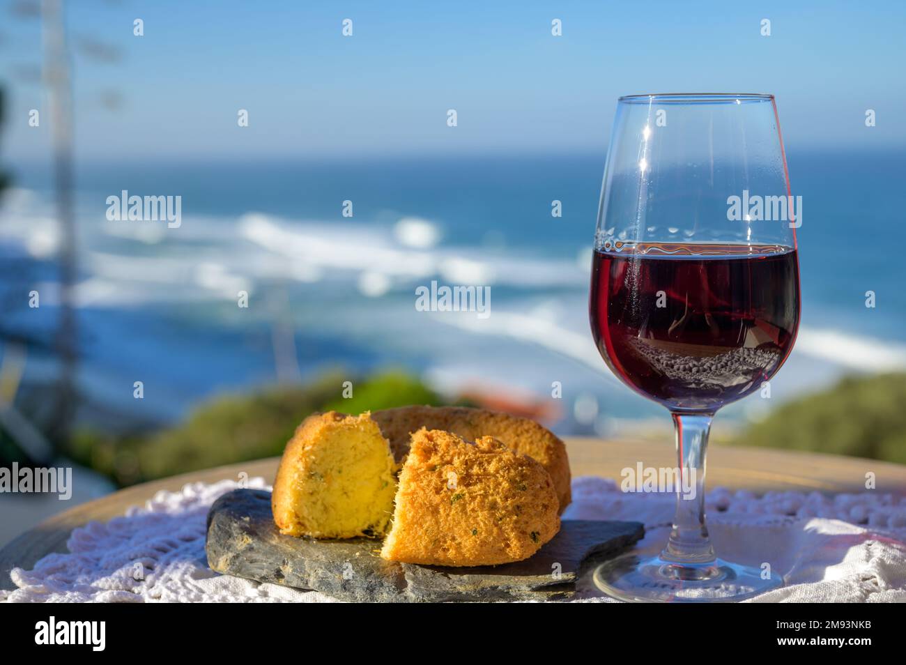 Eine Kombination aus portugiesischen Speisen und Getränken, einem Glas Wein aus dem tawnigen porto und einer Krokodil-Croquette pastais de bacalhau, die im Freien mit Blick auf das blaue, sonnige Atla serviert wird Stockfoto