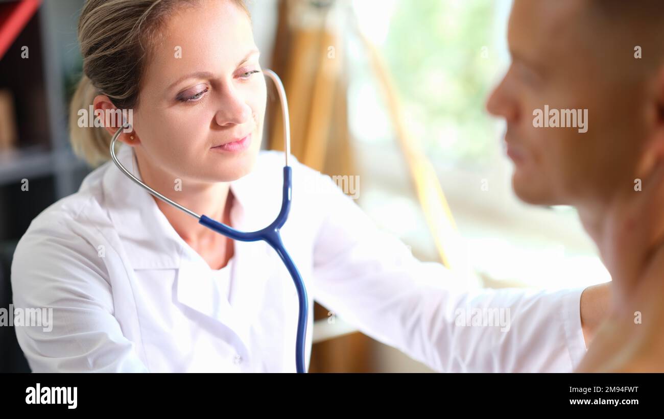 Eine Ärztin mit Stethoskop, die eine medizinische Untersuchung des männlichen Patienten durchführt. Stockfoto