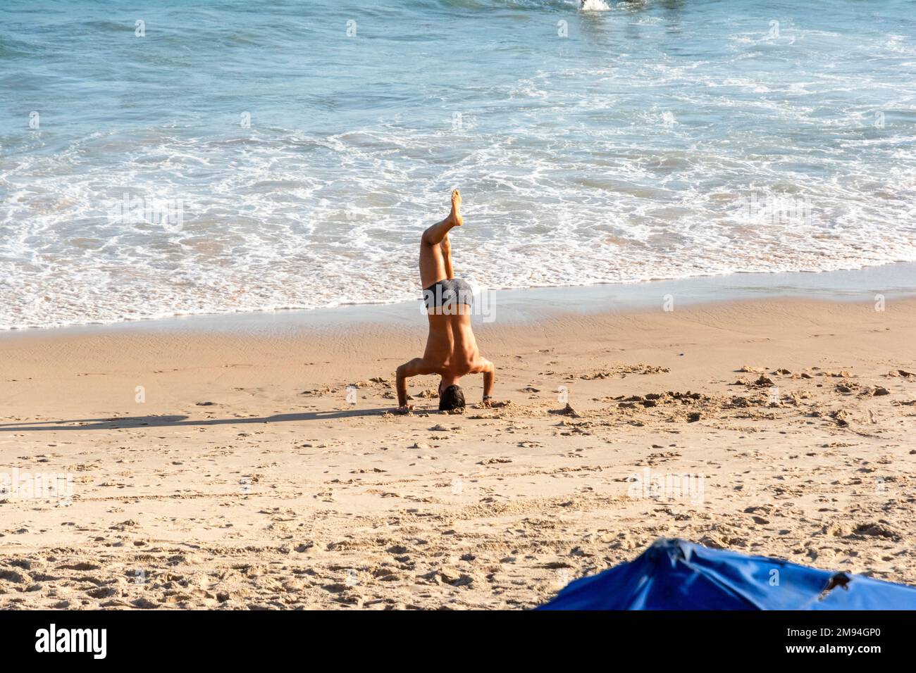 Ein Mann, der Yoga-Übungen am Strand von Farol da Barra macht Stockfoto