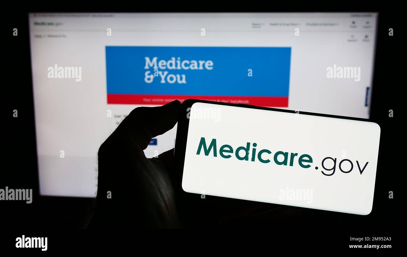 Person mit Mobiltelefon mit Logo des amerikanischen Krankenversicherungsprogramms Medicare auf dem Bildschirm vor der Webseite. Konzentrieren Sie sich auf das Display des Telefons. Stockfoto