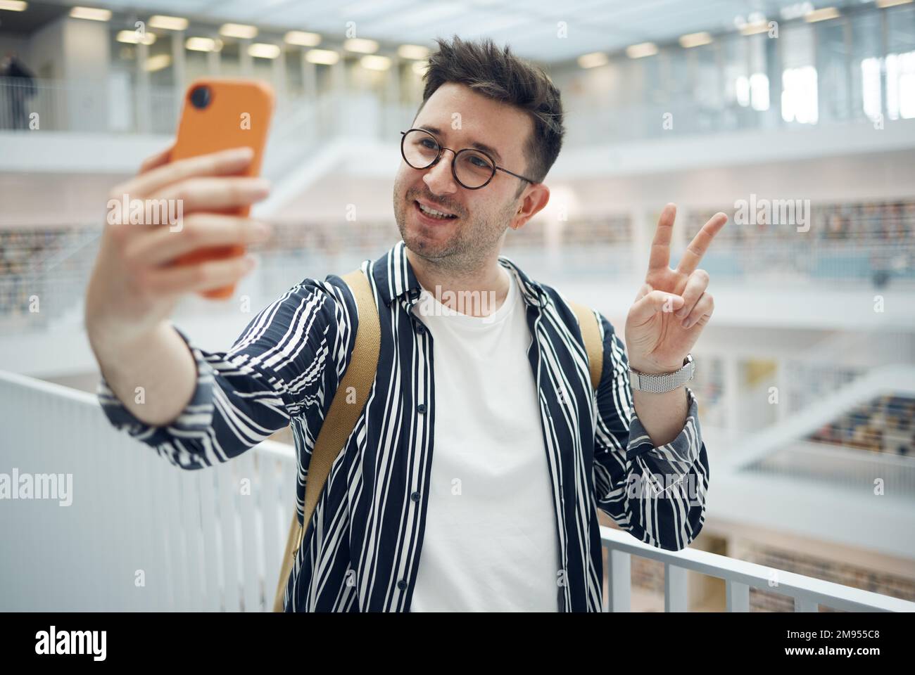 College-Student, Mann und Bibliothek Selfie auf dem Campus mit Telefon, Friedenshand und Lächeln in sozialen Medien. Gen z, Studenten- und Smartphone-App für Stockfoto