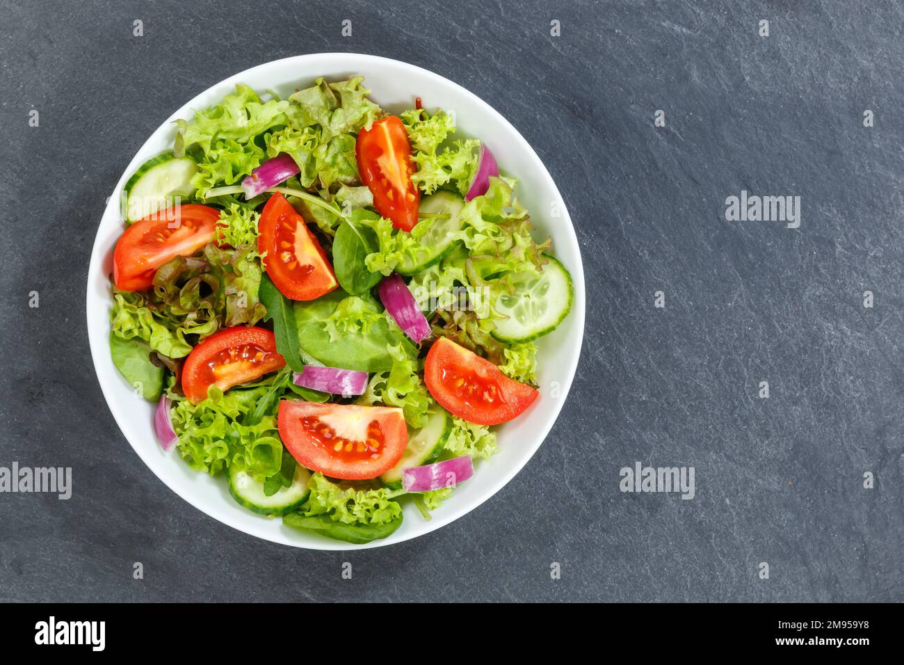 Gemischter Salat mit frischen Tomaten gesundes Essen Essen von oben mit Kopierraum auf einem Schiefer Stockfoto