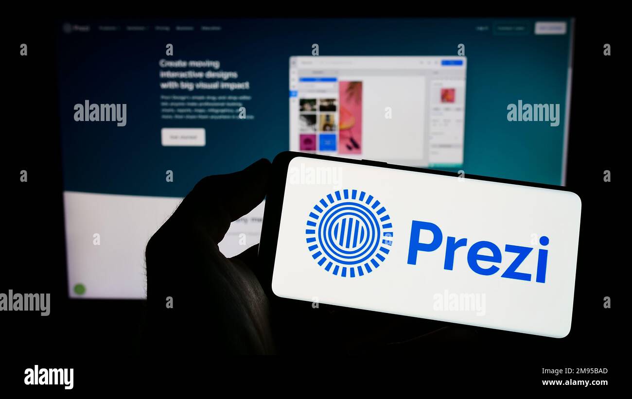 Person, die ein Mobiltelefon mit dem Logo des ungarischen Softwareunternehmens Prezi Inc. Auf dem Bildschirm vor der geschäftlichen Webseite hält. Konzentrieren Sie sich auf das Display des Telefons. Stockfoto