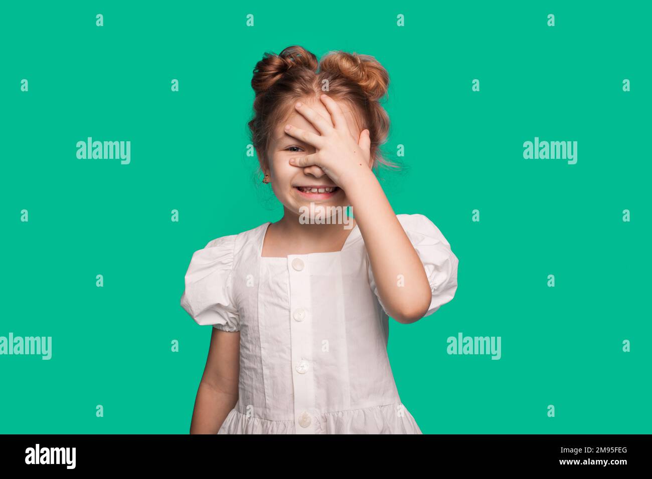 Lächelndes, glückliches Mädchen, das Hand auf Gesicht legt, Gesichtsschmerz isoliert auf einem grünen, hellen Studioporträt im Hintergrund. Stockfoto