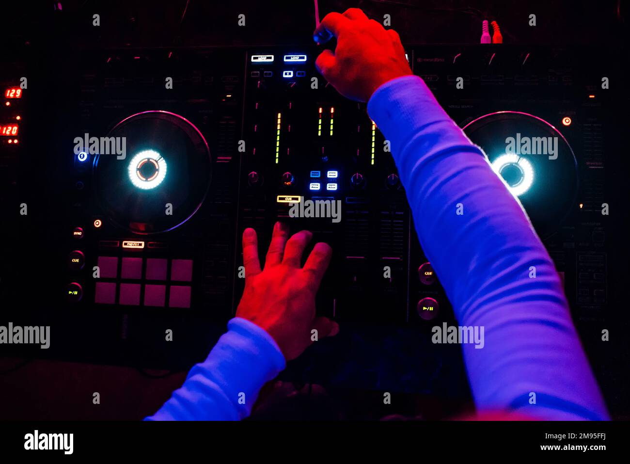 Der DJ spielt bei einem professionellen Mixer Musik auf einer Party mit Blick von oben und dunklem Licht Stockfoto
