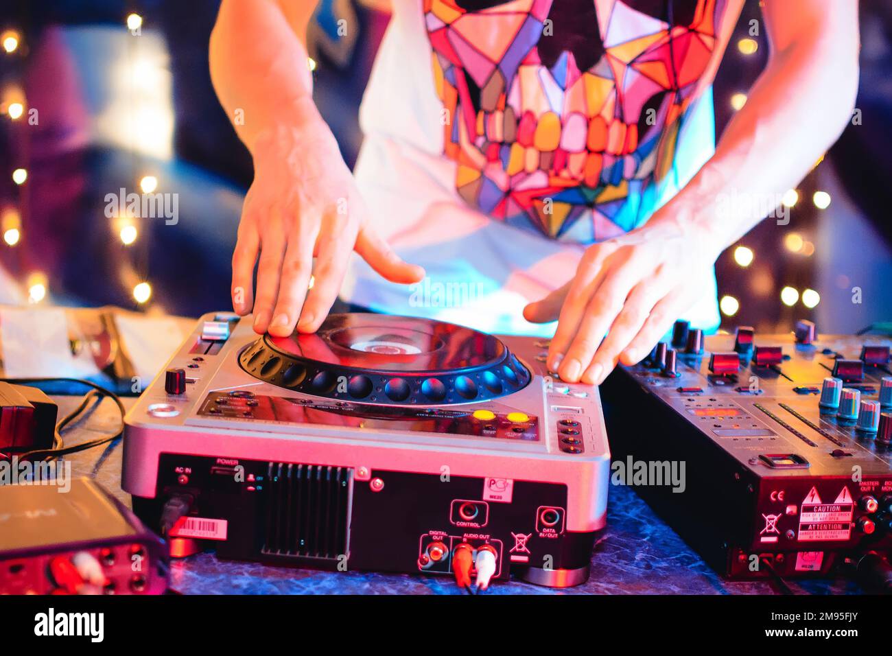 Der DJ im Nachtklub bringt Musik in hellen Farben auf die Konsole Stockfoto