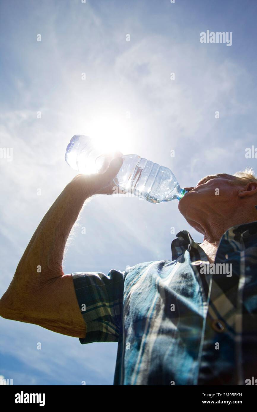 Senioren und Hitzewelle: Immer hydriert. Intensive Hitze: Alter Mann trinkt Wasser. Illustration, ältere Menschen und Hydratation, Dehydratationsrisiko Stockfoto