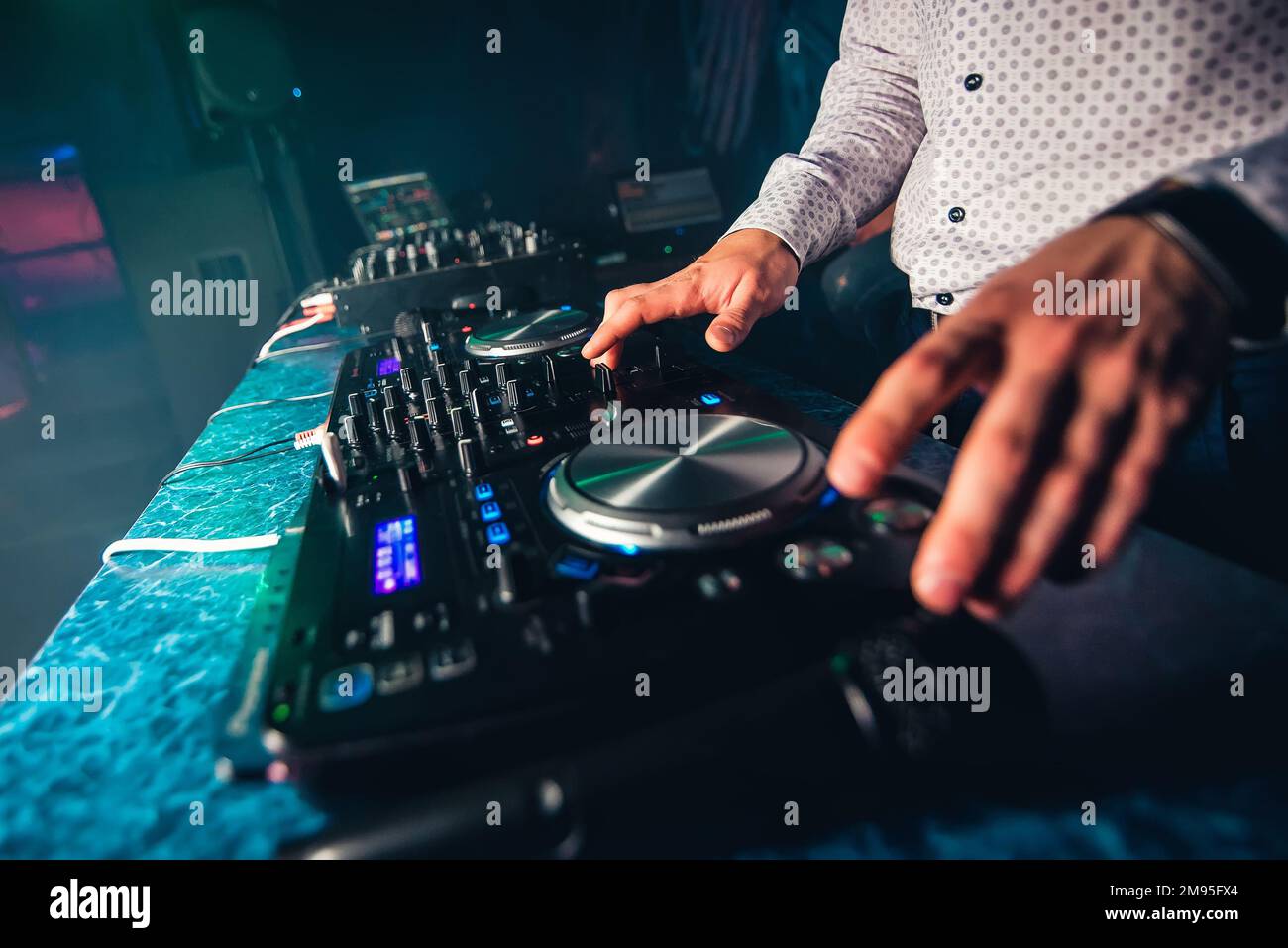 Der DJ spielt Musik im Nachtclub auf der Party, indem er die Knöpfe und die Lautstärke steuert Stockfoto