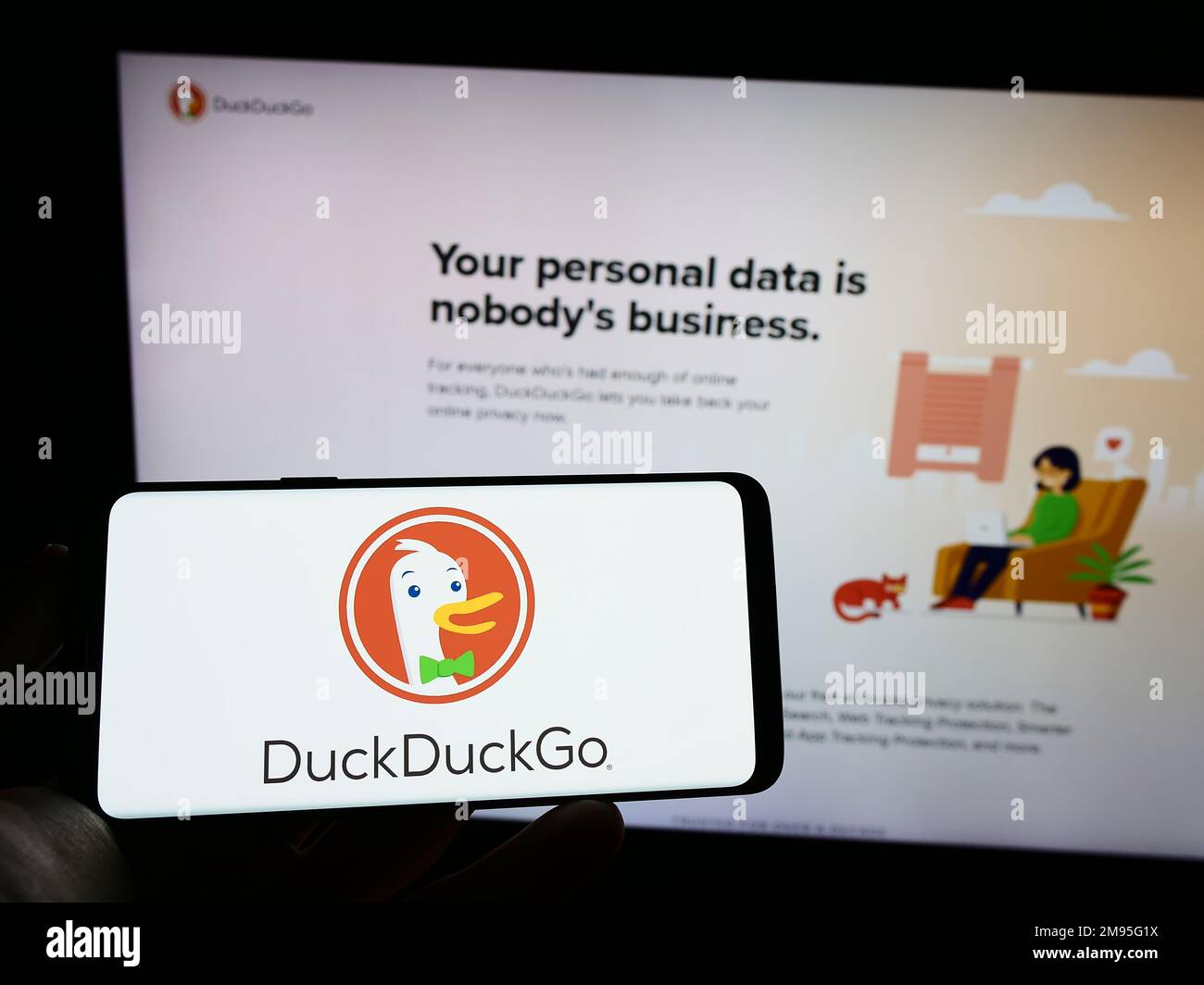 Person, die ein Mobiltelefon mit dem Logo der Internet-Suchmaschine DuckDuckGo (DDG) auf dem Bildschirm vor der Unternehmenswebseite hält. Konzentrieren Sie sich auf das Display des Telefons. Stockfoto