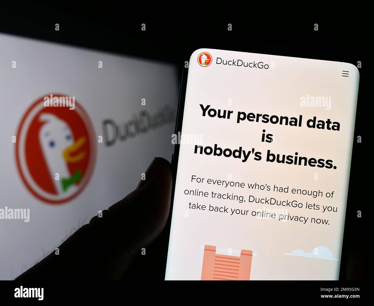 Person, die ein Smartphone mit einer Webseite der Internet-Suchmaschine DuckDuckGo (DDG) auf dem Bildschirm vor dem Logo hält. Konzentrieren Sie sich auf die Mitte des Telefondisplays. Stockfoto