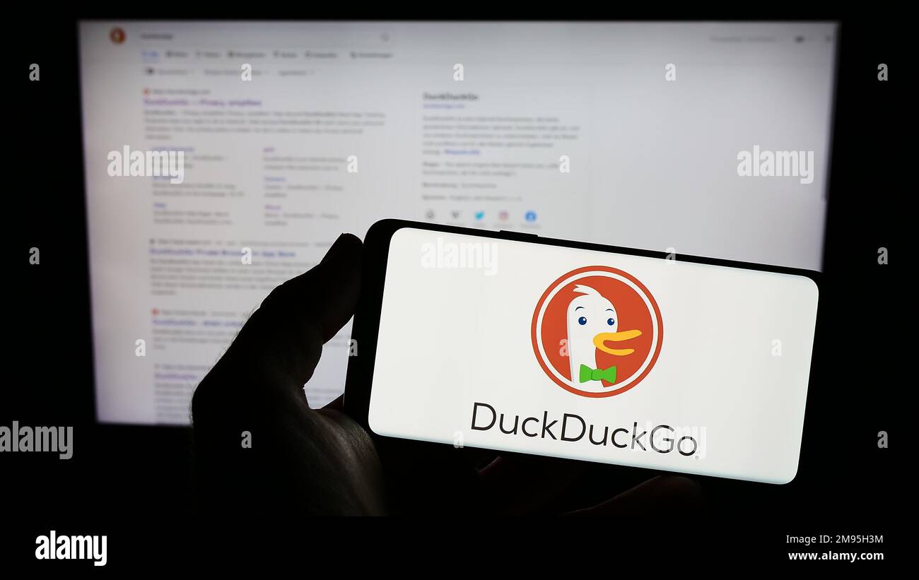 Person, die ein Smartphone mit dem Logo der Internet-Suchmaschine DuckDuckGo (DDG) auf dem Bildschirm vor der Website hält. Konzentrieren Sie sich auf das Display des Telefons. Stockfoto
