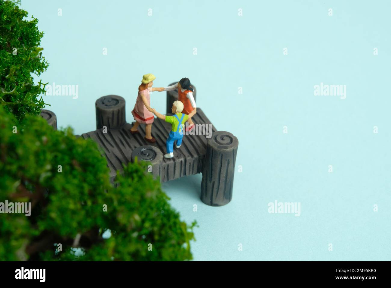 Miniatur-Menschen-Spielzeug-Figuren-Fotografie. Gefährlicher Ort zum Spielen für das Kind. Kinder, die über dem Bridge Lake River spielen. Bildfoto Stockfoto