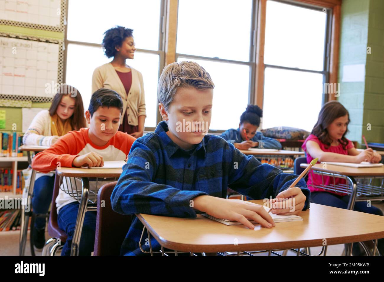 Junge, Klassenraum, Schreibdienst, Schule und Fokus auf Bildung, Entwicklung und Lernen für die Zukunft. Schulkinder, Lehrer und Studierende Stockfoto