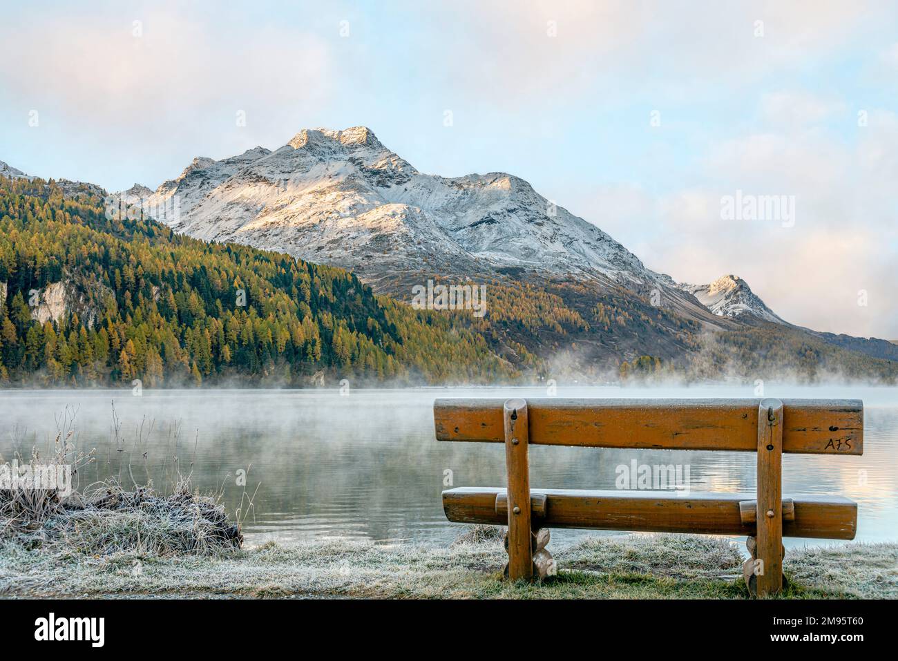 Einsame und leere Bank in Herbstlandschaft am Lake Sils, Engadine, Schweiz, mit Piz Margna im Hintergrund Stockfoto