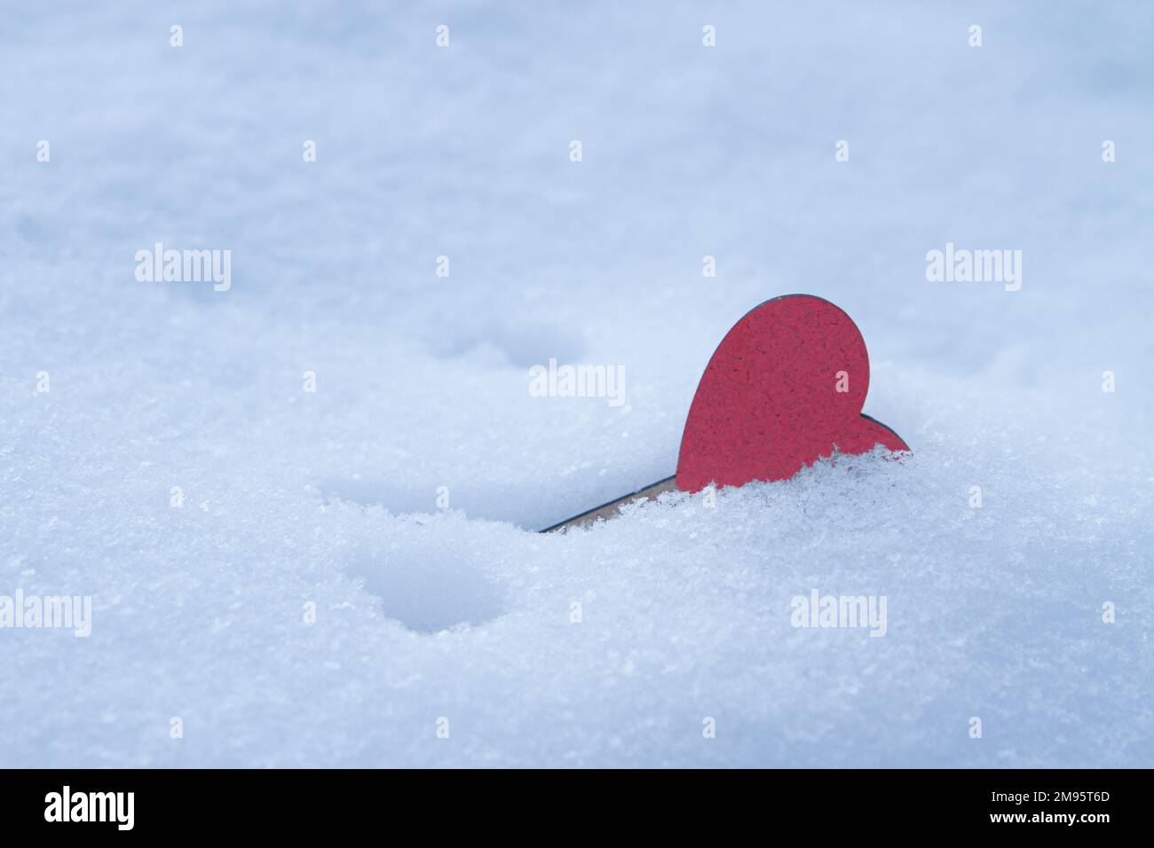 Rotes Herz begraben in weißem, flauschigem Schnee Stockfoto