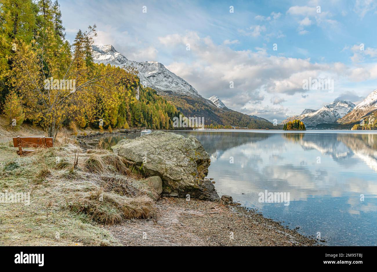 Parkbank in Herbstlandschaft am Lake Sils, Engadine, Schweiz mit Piz Margna im Hintergrund Stockfoto