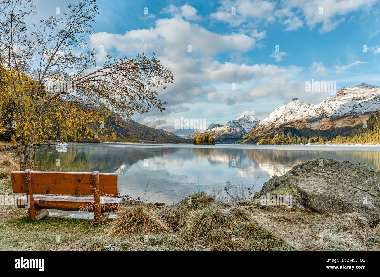 Einsame und leere Bank in Herbstlandschaft am Lake Sils, Engadine, Schweiz, mit Piz Margna im Hintergrund Stockfoto
