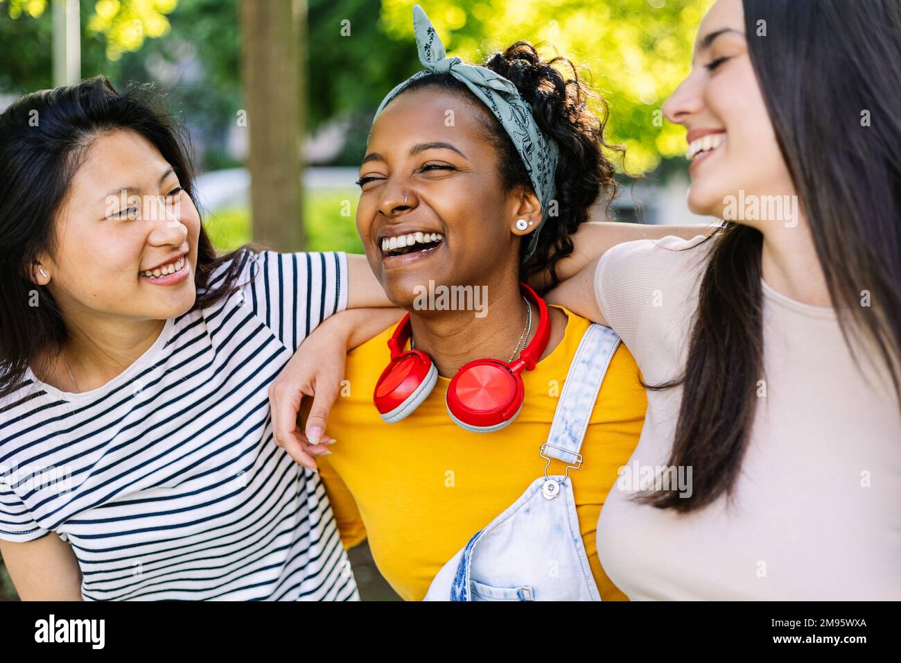 Drei zusammengetragene, multiethnische, weibliche Freunde, die Spaß haben, draußen zusammen zu lachen Stockfoto