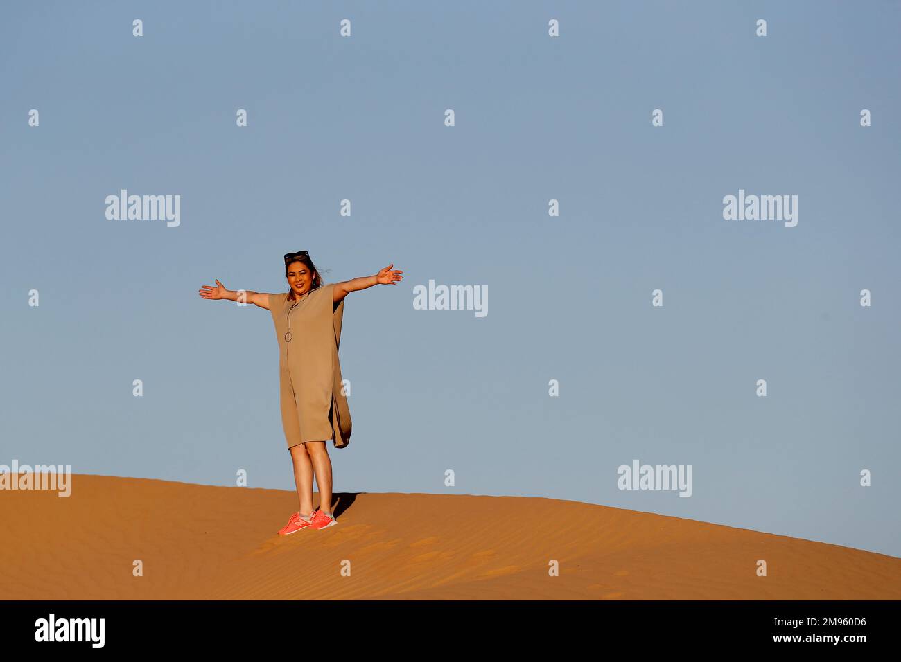 Eine Frau, die allein auf einer Sanddüne in Richtung der arabischen Wüste läuft. Vereinigte Arabische Emirate. Stockfoto