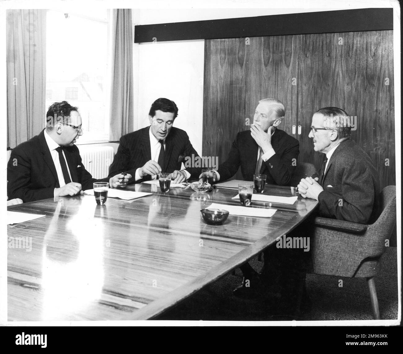 Es findet eine Vorstandssitzung statt. Eine Gruppe von Männern sitzt am Vorstandstisch und raucht und diskutiert verschiedene Themen. Stockfoto