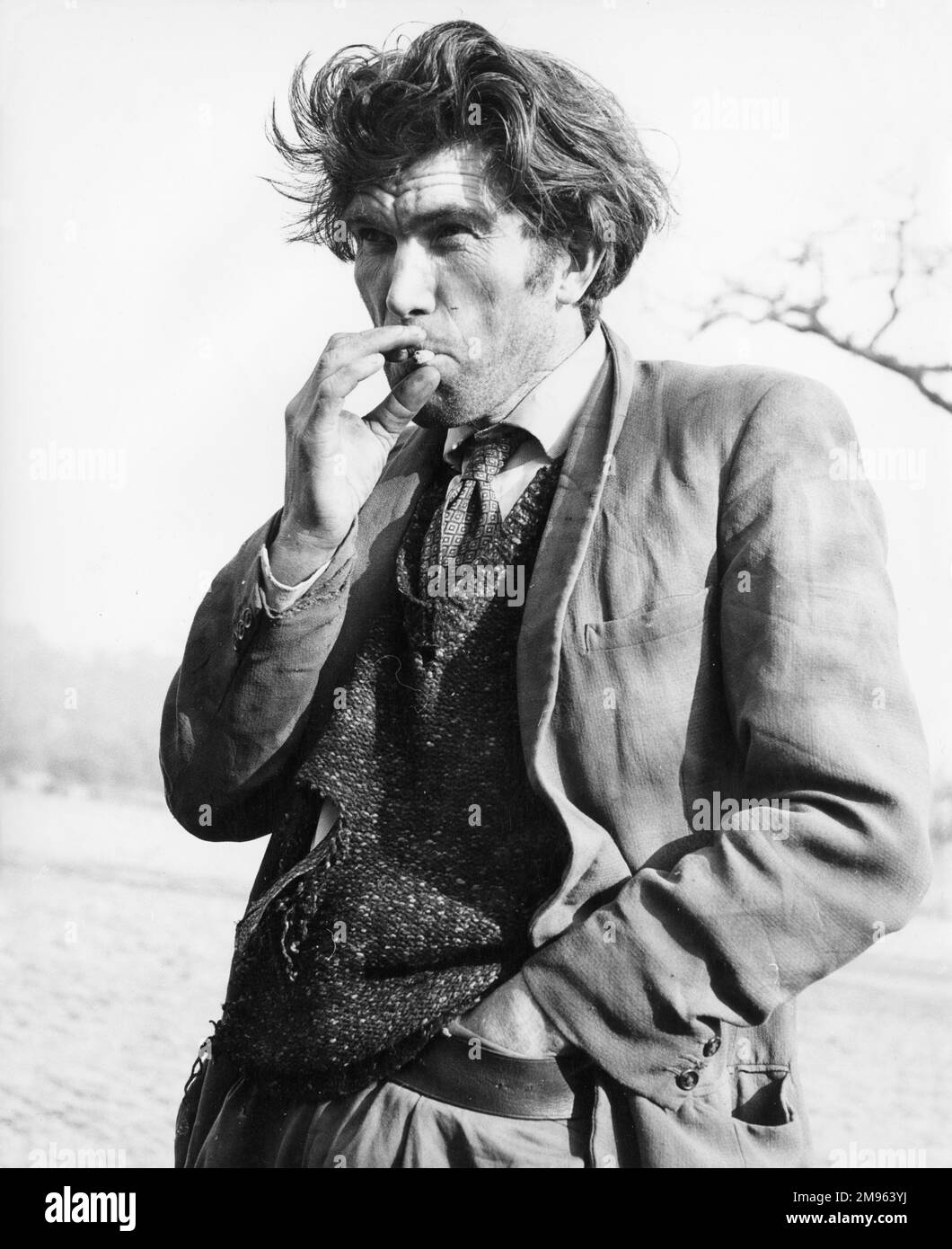 Ein Zigeuner mittleren Alters, rauchend, mit einer Hand in seinem Gürtel. Stockfoto