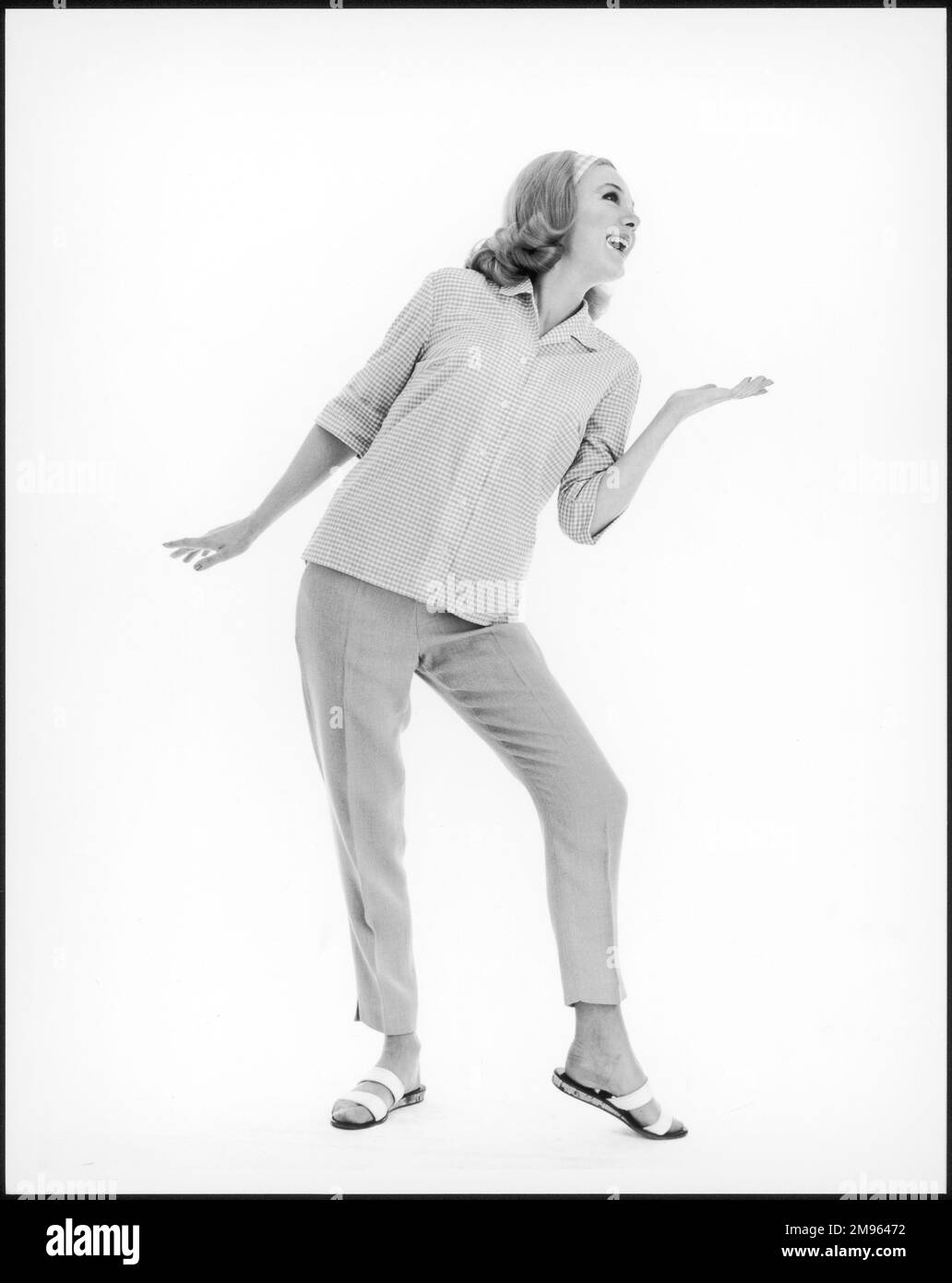 Durchgehendes Foto eines Modells aus den Sechzigern, das ein kariertes Hemd, kurze Hosen und Sandalen trägt Stockfoto