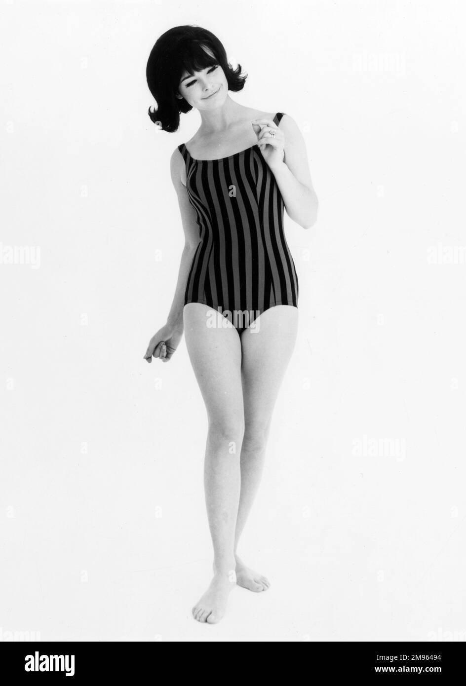 Ein langes Foto einer Frau in einem gestreiften Badeanzug, die ein bisschen tanzt. Stockfoto