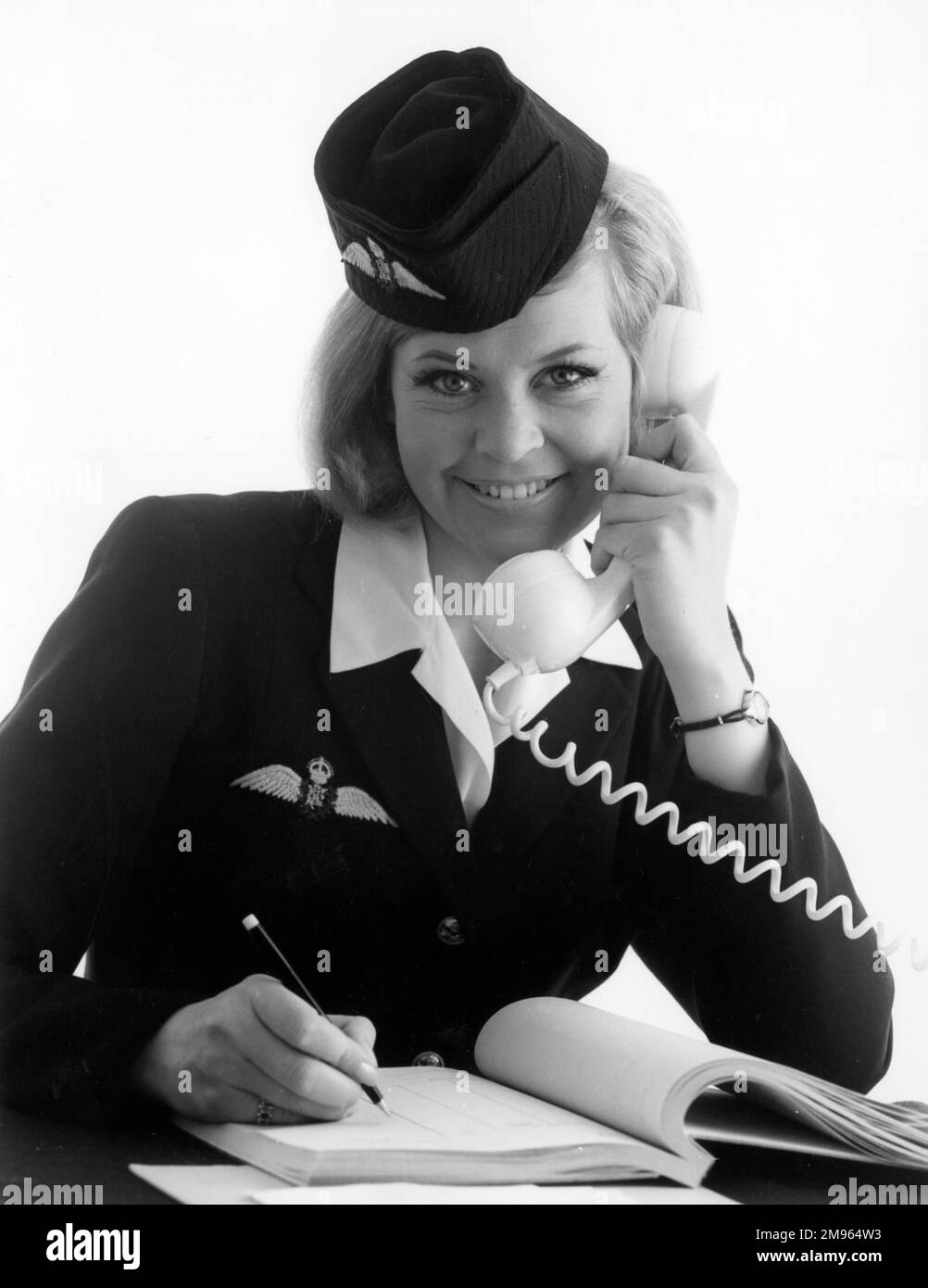 Eine Stewardess schreibt in ein Buch, während sie am Telefon spricht. Stockfoto