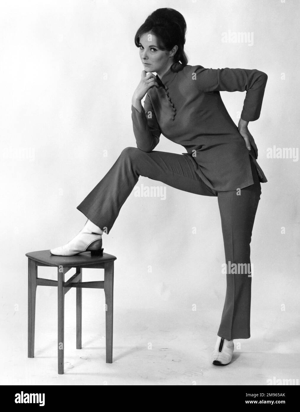 Eine Frau posiert mit einem Fuß auf dem Hocker. Stockfoto