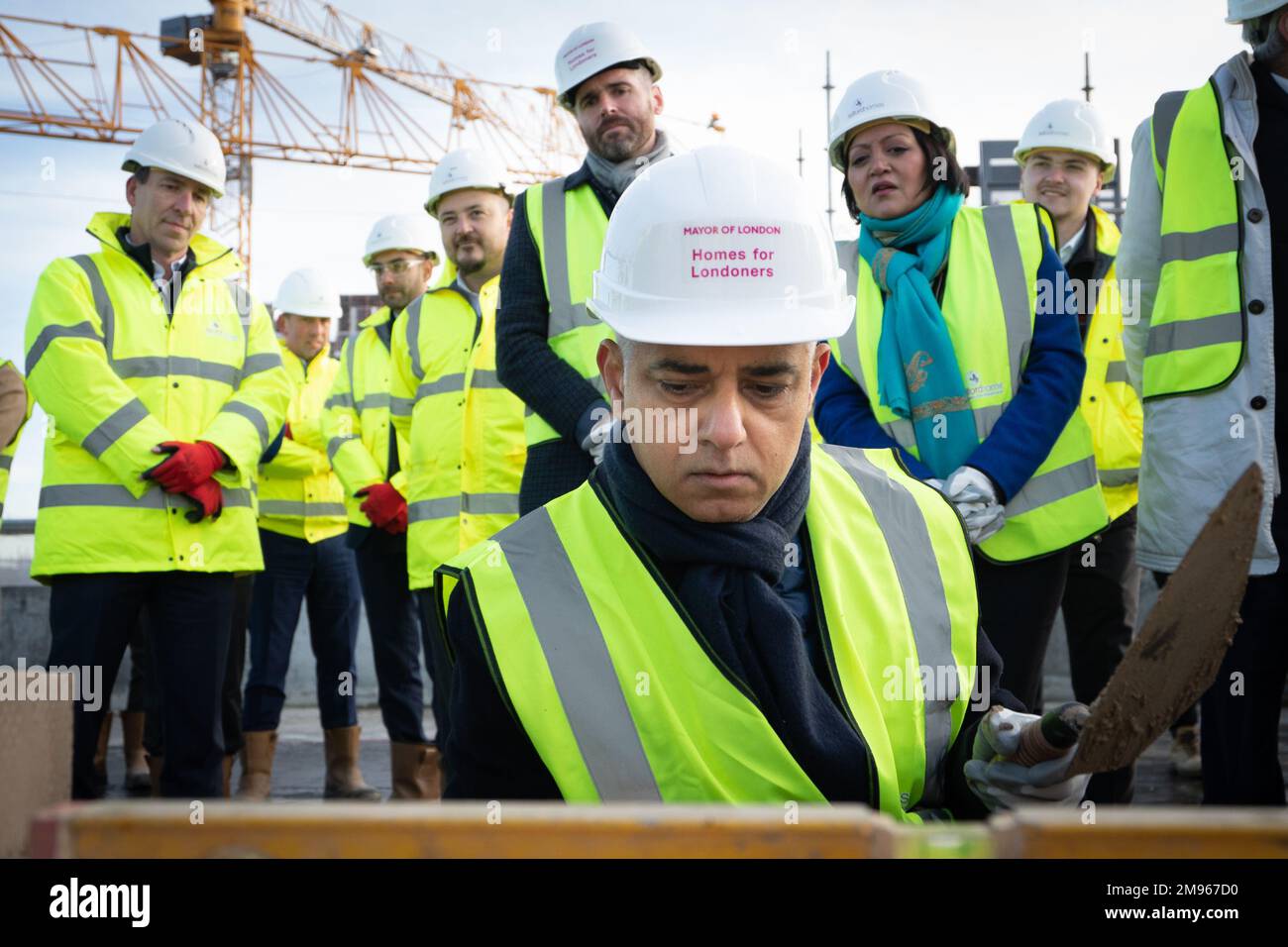 Der Bürgermeister von London, Sadiq Khan, versucht seine Hand beim Ziegelsteinlegen während der Bestattungszeremonie für ein neues bezahlbares Wohnungsbauprojekt in den Royal Docks im Osten Londons, wo er ankündigte, dass unter ihm mehr neue Häuser fertig gestellt wurden als unter jedem früheren Londoner Bürgermeister. Foto: Dienstag, 17. Januar 2023. Stockfoto