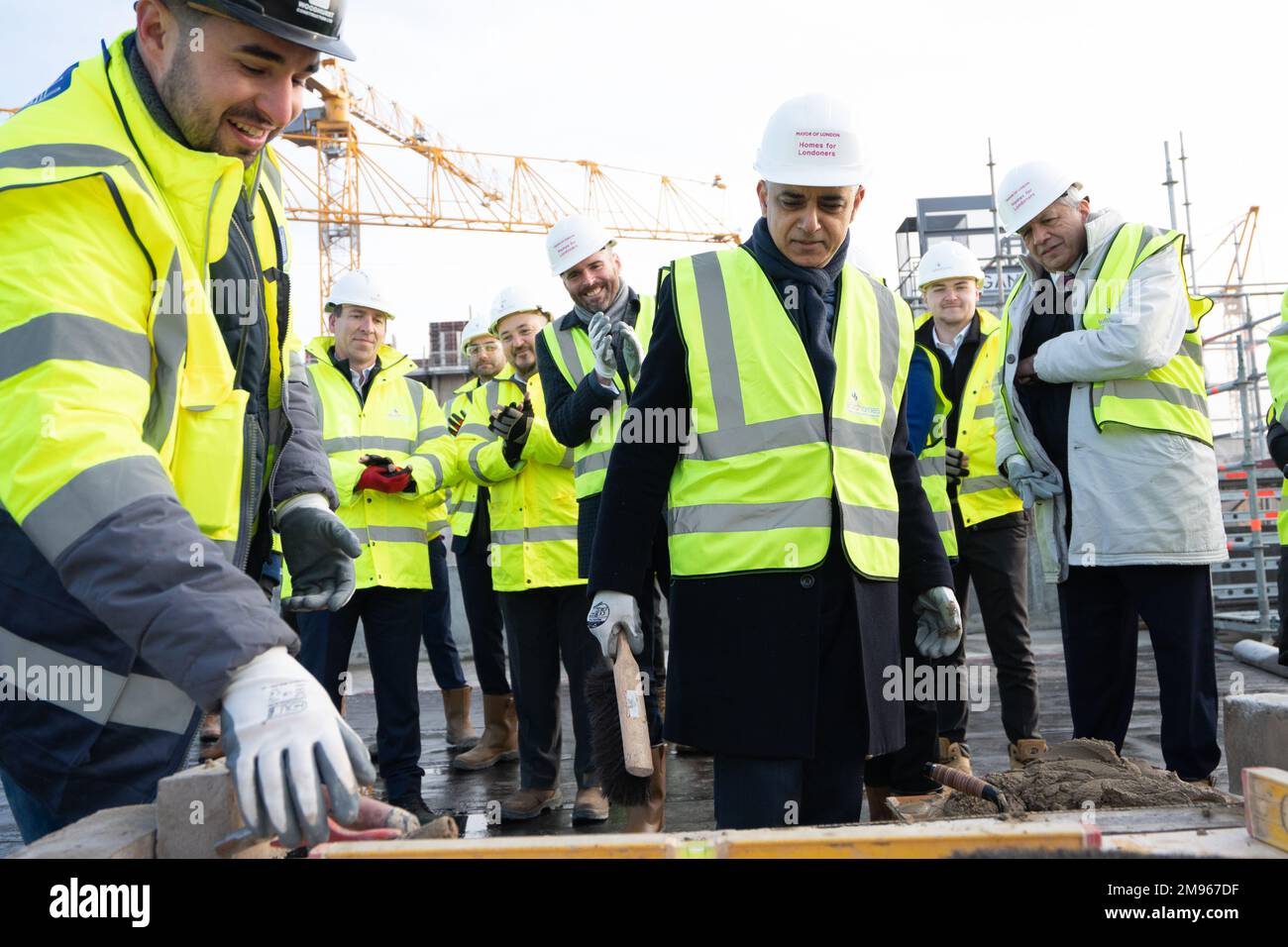 Der Bürgermeister von London, Sadiq Khan, versucht seine Hand beim Ziegelsteinlegen während der Bestattungszeremonie für ein neues bezahlbares Wohnungsbauprojekt in den Royal Docks im Osten Londons, wo er ankündigte, dass unter ihm mehr neue Häuser fertig gestellt wurden als unter jedem früheren Londoner Bürgermeister. Foto: Dienstag, 17. Januar 2023. Stockfoto