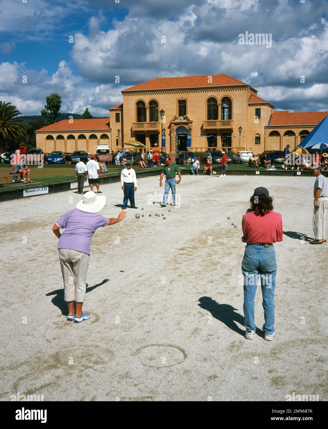 Leute spielen Boule in Government Gardens, Rotorua, North Island, Neuseeland. Das Gebäude im Hintergrund ist das Blue Baths, ein historisches Zentrum, das 1933 erbaut wurde und ein Wellnesscenter, Swimmingpools und Räume für gesellschaftliche und geschäftliche Veranstaltungen kombiniert. Stockfoto